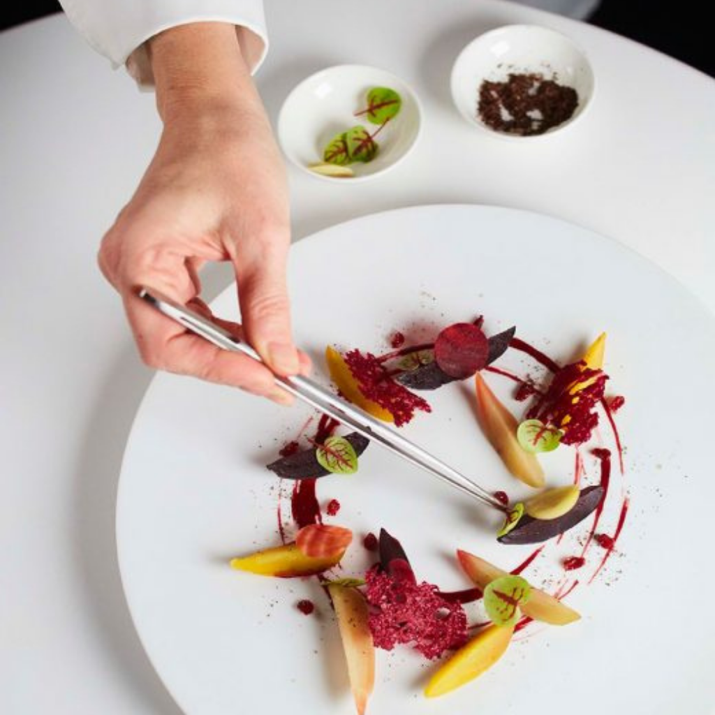 A close up of a colourful plate of food, being plated up by Pic using tweezers